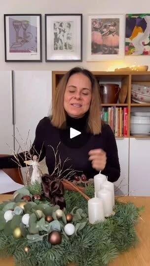 a woman sitting at a table with candles in front of her and christmas decorations around her