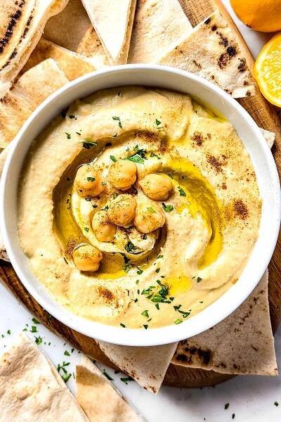 Hummus in bowl with drizzle of olive oil and pita on side