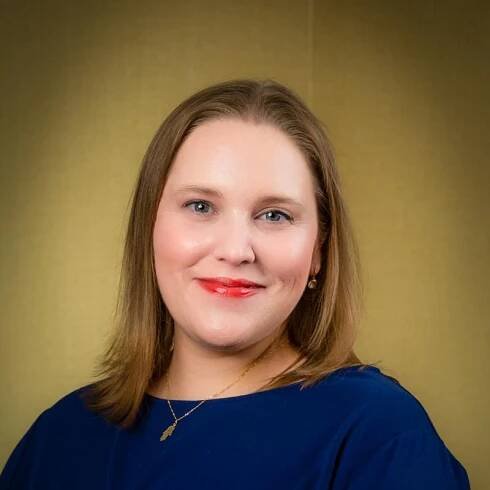 Blonde cantor Mary Thomas smiling at the camera. Long hair, blue eyes, wearing a blue dress