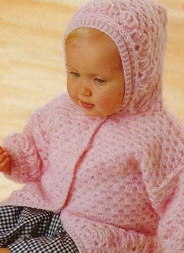 a baby wearing a pink knitted sweater and hat