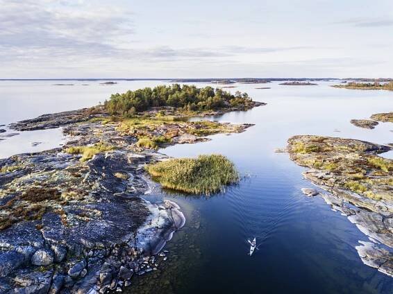 A person kayaking between small islands in lake Vänern during summer.