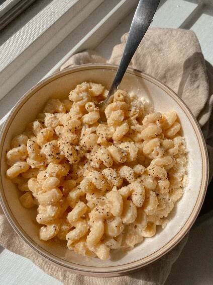 creamy cavatappi pasta in a white bowl with a dish towel