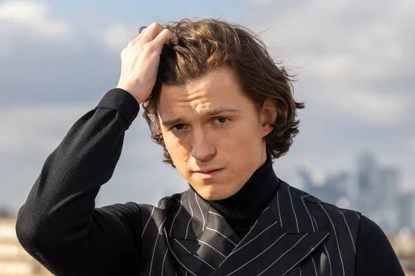 Person in pinstripe suit and turtleneck, outdoors, touching head with hand, looking thoughtful. Skyscrapers in the background