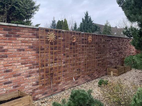 a brick wall with wooden planters in the foreground and trees in the background
