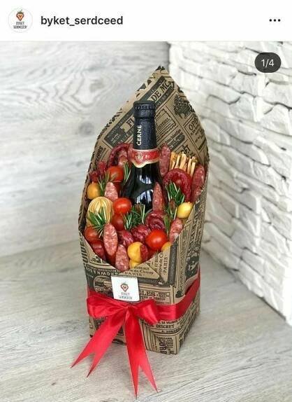 a wine bottle wrapped in paper with tomatoes and sausages on it, sitting next to a brick wall