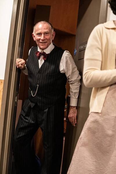 Danny Webb stands in the doorway of his dressing room, he looks directly at the camera and smiles.