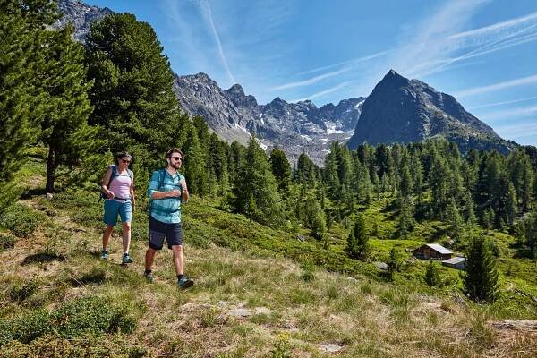 Zwei Wanderer auf einem Wiesenpfad mit Ausblick auf einen markanten Berggipfel