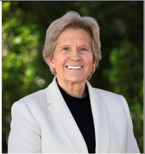 Mature, professional woman in white blazer and black shirt.