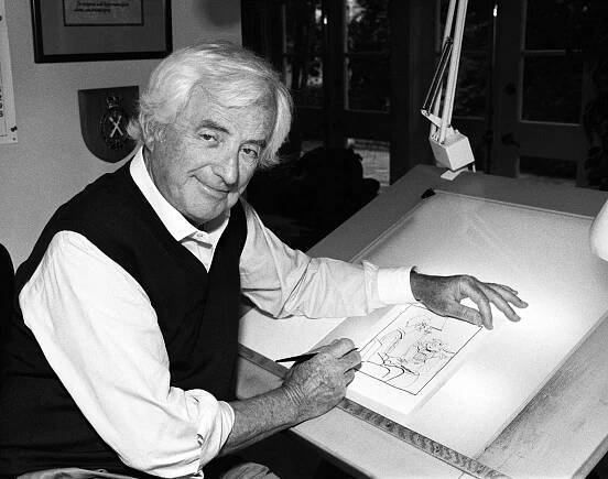 Portrait of cartoonist Hank Ketcham as he sits at a drawing table in his studio, California, circa 1993