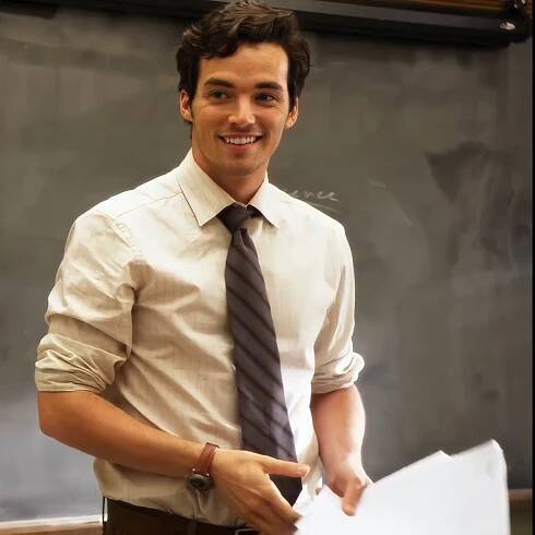 a man wearing a tie standing in front of a blackboard