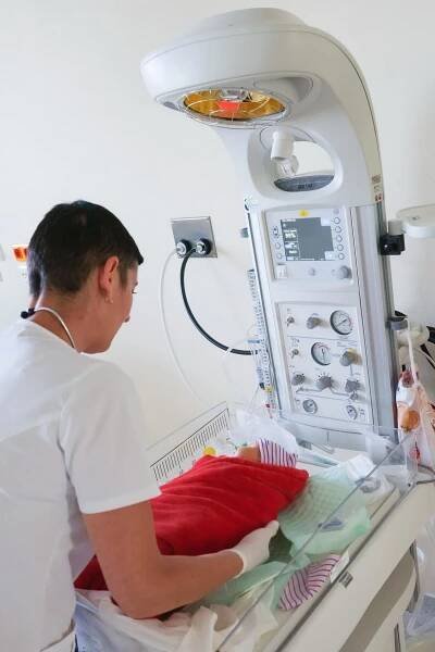 Porodnice Kolín. Oblastní nemocnice Kolín a.s., Gynekologicko-porodnické oddělení: Sestřička kontrolující nově narozené miminko.