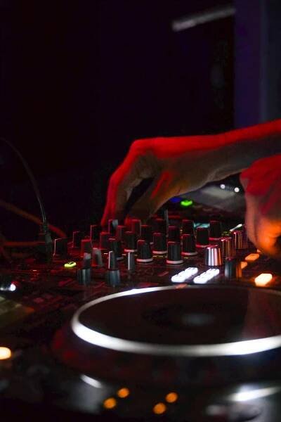 Free Close-up of DJ hands mixing music on a console, illuminated by vibrant lights. Stock Photo