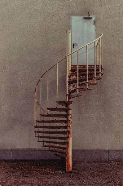 bezplatná K zavřeným dveřím na betonové stěně vede rustikální točité schodiště s viditelným rozpadem. Základová fotografie