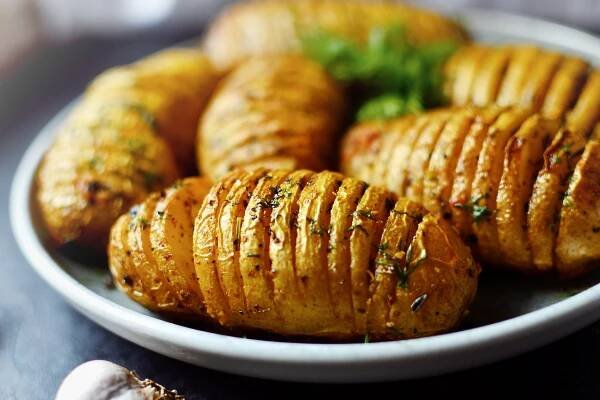 Hasselback potatoes Baked accordion potatoes Delicious vegetables Food in a gray clay plate close up