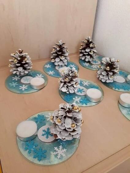 some pine cones and candles are sitting on plates with snowflakes around them,