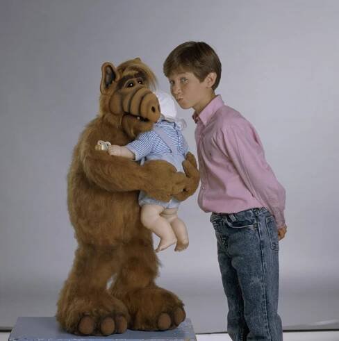 Actor Benji Gregory, best known for his role in the sitcom 'Alf', kissing a person in a garment