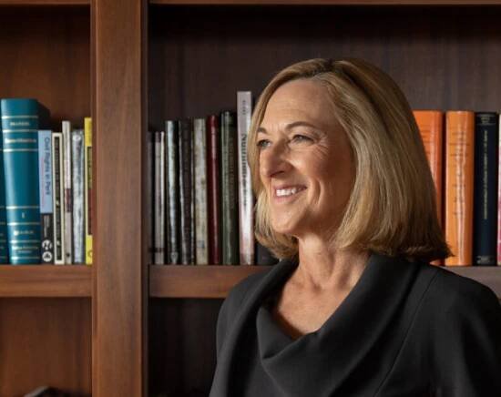 Dean Susan Fournier standing in front of bookshelf