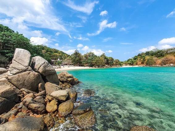 Scenic beach with turquoise water and rocky shore in Phuket, Thailand.