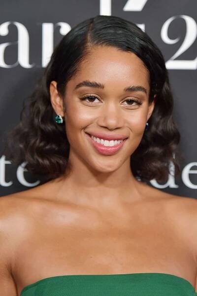 Laura Harrier in a curly long bob hairstyle tucked behind the ear with a side part
