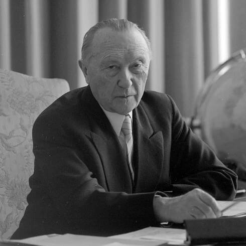 Schwarz-Weiss-Aufnahme von Konrad Adenauer am Schreitisch sitzend