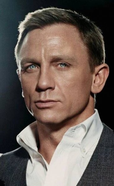 a close up of a person in a suit and tie with blue eyes looking at the camera