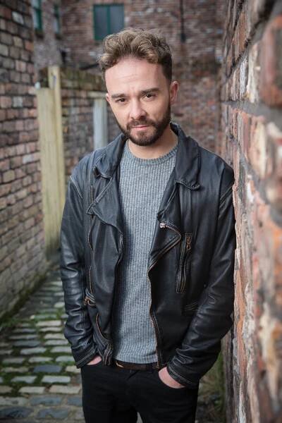 Jack P. Shepherd, Coronation Street actor, leaning against a brick wall.