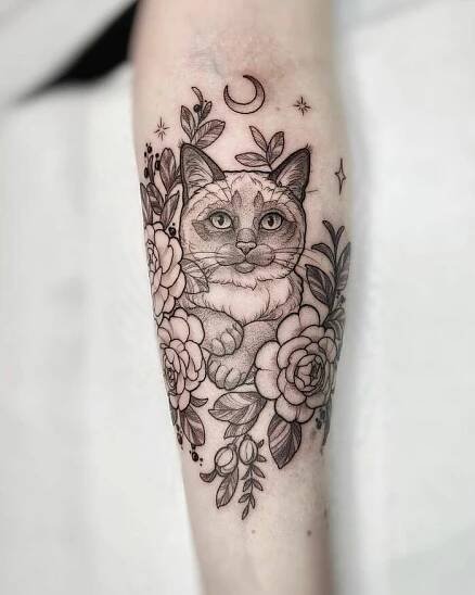 Cat and floral memorial tattoo design on forearm, featuring a crescent moon and stars.