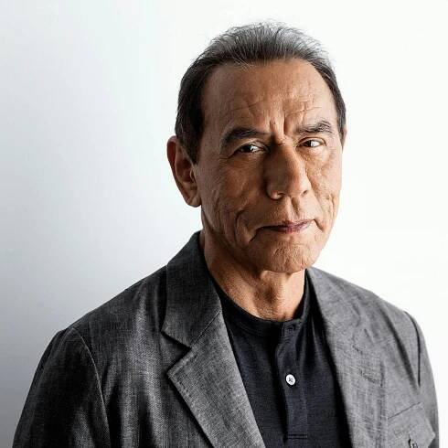 Portrait of actor Wes Studi wearing a gray sport coat and black shirt.