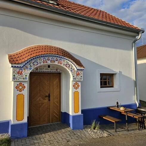 a building with a wooden door and a bench at Pod vinohradem - apartmány & vinné sklepy in Mutěnice