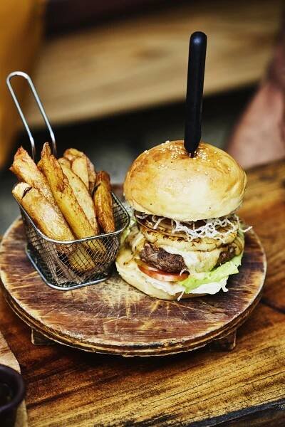a hamburger and french fries on a wooden plate