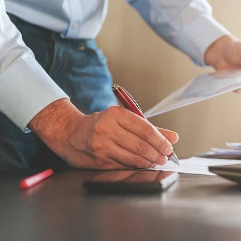 Close-up of a person's hands writing on a paper. 