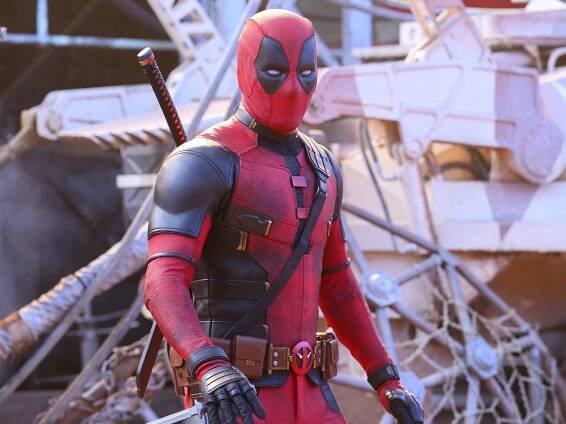 Deadpool wearing a red and black suit, holding a small knife.