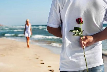 Stáhnout - Romantické rande koncept - muž s růží čeká ženu na mořské pláži na léto — Stock obrázek