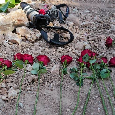 Red roses and cameras laid on the grave of a Reuters journalist.
