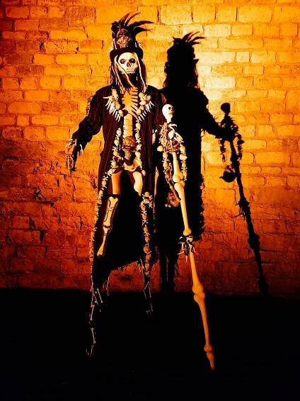 Stilt-walking skeleton spider and voodoo priest.