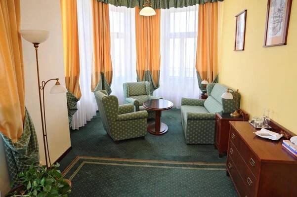 a hotel room with chairs and a table and windows at Grandhotel Garni in Jihlava