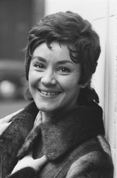 In a black and white photo, Edith Mathis smiles at the camera.