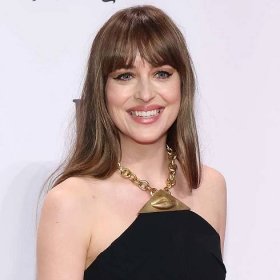 Dakota Johnson wears a long, cool brown hairstyle with bangs and a Schiaparelli jewelry halter top