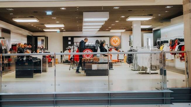 Blick in den hell erleuchteten Eintracht Frankfurt Fanshop mit Kleidung und Accessoires.