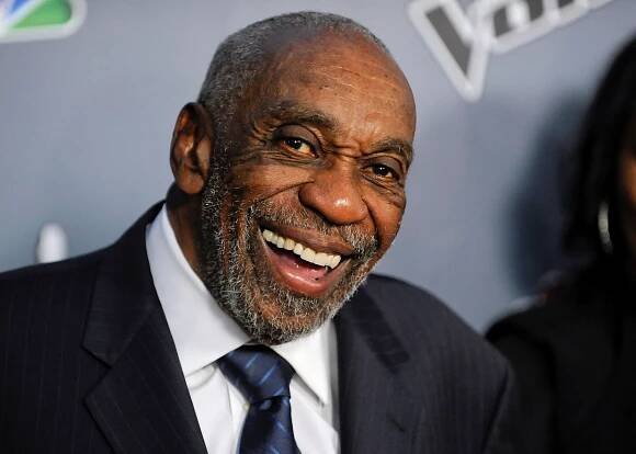 Bill Cobbs as an older man, smiling and wearing a suit.