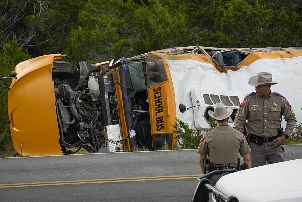 Overturned school bus at crash scene with state troopers.