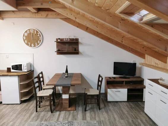 a kitchen and dining room with a table and a clock at Apartmány Nová duha Vavřinec in Vavřinec