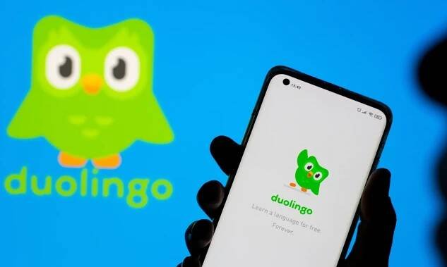 Woman with her smartphone poses in front of displayed Duolingo logo in this illustration taken, June 29, 2021. REUTERS/Dado Ruvic