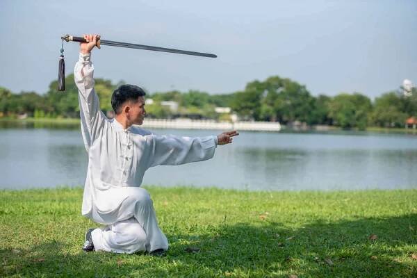 Asian man practicing with Tai Chi sword in the morning at the park