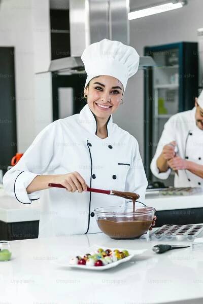 latin woman pastry chef wearing uniform holding a bowl preparing delicious sweets chocolates at kitchen in Mexico Latin America