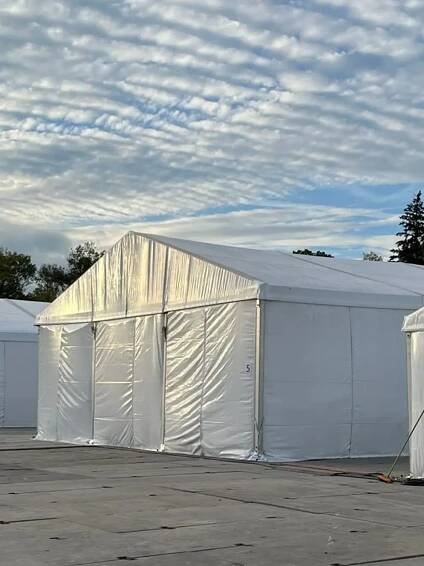 Multiple Medium sized white tents set up on asphalt for base camp