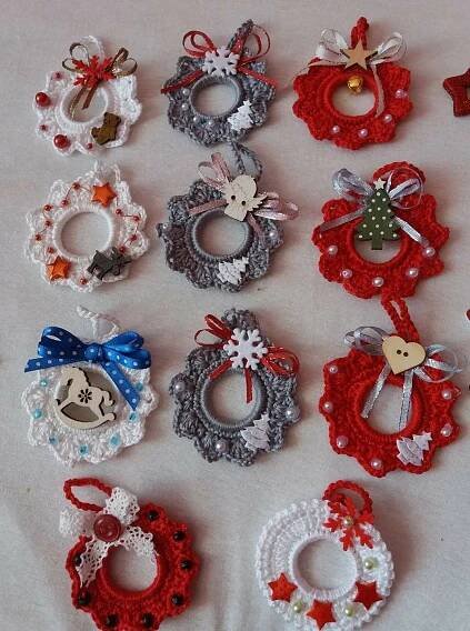 crocheted christmas ornaments are laid out on a table top, including wreaths and bells