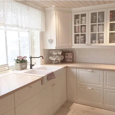 a kitchen with white cabinets and counter tops next to a window filled with glass panes