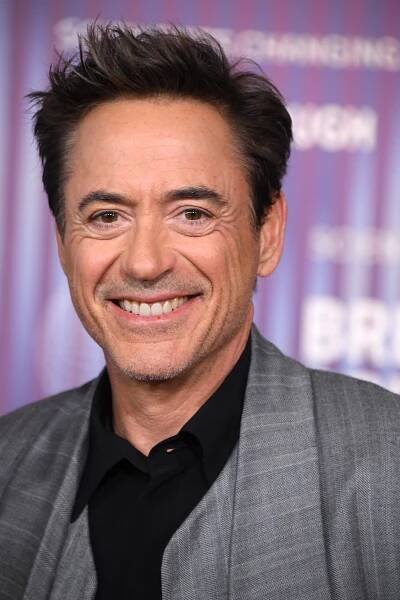 robert downey jr. smiles in front of a sign that says breaking