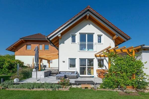 Modernes Einfamilienhaus in Österreich mit Dachgaube und hellem Außenbereich, umgeben von gepflegtem Garten. Perfektes Beispiel für Hausumbau und Aufstocken zur Schaffung von mehr Wohnraum.